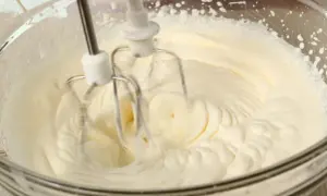 Ubity krem śmietankowy do tortu bez mascarpone, przygotowywany mikserem w szklanej misie.