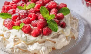 Beza Pavlova, która zawsze wychodzi, obficie udekorowana malinami i listkami mięty, posypana cukrem pudrem.