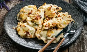 Talerz pełen pysznych, domowych pierogów okraszonych skwarkami. Idealne, gdy zastanawiasz się, ile gotować pierogi, by były miękkie i smaczne.