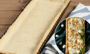 Pusta, upieczona masa do mazurka w formie czeka na nadzienie. Obok w okręgu widać gotowy mazurek z migdałami.