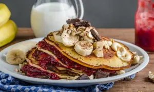 Stos puszystych, trzyskładnikowych placków bananowych z malinową konfiturą, bananami, orzechami i czekoladą.