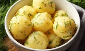 A white bowl filled with fluffy ziemniaki na parze, sprinkled with fresh dill.
