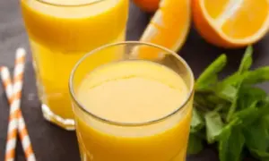 Dwa szklanki świeżego soku pomarańczowego, plasterki pomarańczy i listki mięty. Pyszny napój, który nie ma zbyt wielu pomarańcza kcal.