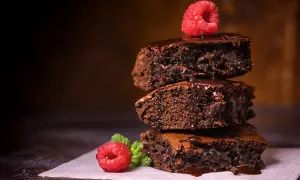 Stos pysznych, wilgotnych brownie z polewą czekoladową i malinami. Idealny brownie prosty przepis na domowe ciasto.