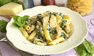 Pyszny makaron ze szpinakiem i kurczakiem w kremowym sosie śmietanowym, posypany parmezanem. Idealny na szybki obiad.