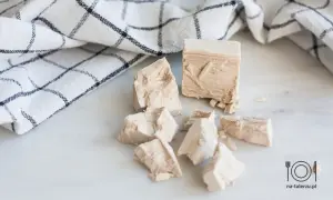 Kostki świeżych drożdży, gotowe do pieczenia pysznego ciasta drożdżowego. Obok leży biały ręcznik w kratkę.