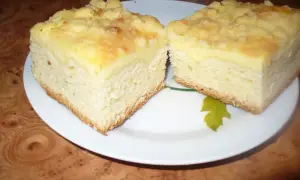 Dwa kawałki puszystego ciasta drożdżowego z serem, posypane kruszonką, na białym talerzu.
