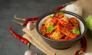 Miseczka z pikantnym kimchi, obok papryczki chili i czosnek. Idealne składniki, by dowiedzieć się, jak zrobić kimchi.