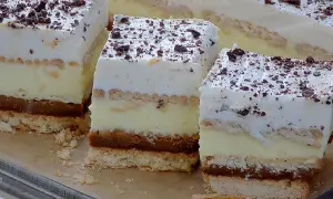 Kawałki ciasta 3 Bit z kremem, biszkoptem i polewą czekoladową, posypane wiórkami.