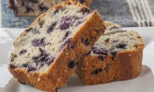 Szybkie i proste ciasto z jagodami, pokrojone na kromki, leży na białym talerzu.