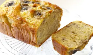 Wilgotne ciasto bananowe, pachnące i puszyste, z kawałkami bananów na wierzchu, prezentuje się apetycznie na szklanej paterze.