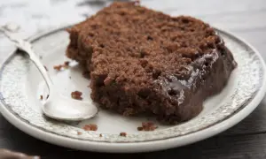 Wilgotny murzynek ciasto z polewą czekoladową na talerzyku, obok srebrna łyżeczka.