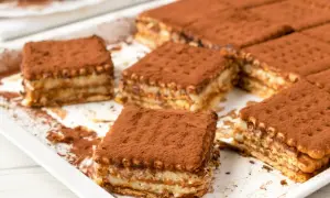 Pyszne, tanie ciasto bez pieczenia z herbatnikami, posypane kakao. Idealne na deser.