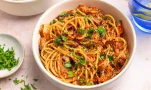 Miseczka spaghetti z sosem pomidorowym, grzybami i posiekaną natką pietruszki.