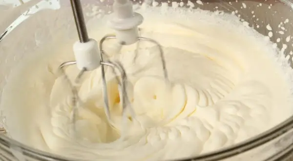 Ubity krem śmietankowy do tortu bez mascarpone, przygotowywany mikserem w szklanej misie.