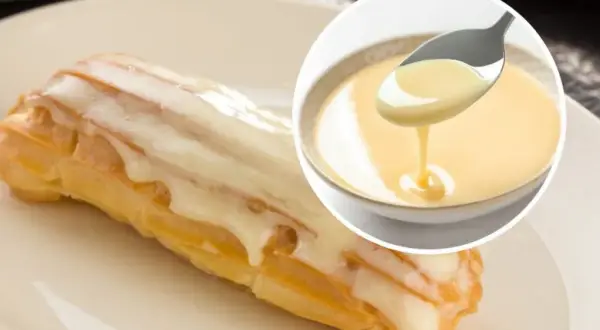 Słodki ekler oblany lukrem, obok miseczka z kremowym custard. Pyszny deser!