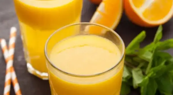 Dwa szklanki świeżego soku pomarańczowego, plasterki pomarańczy i listki mięty. Pyszny napój, który nie ma zbyt wielu pomarańcza kcal.