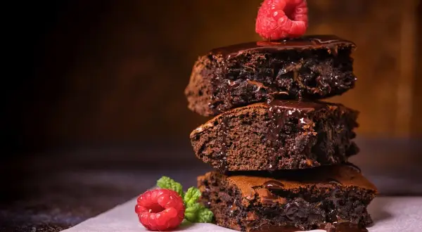 Stos pysznych, wilgotnych brownie z polewą czekoladową i malinami. Idealny brownie prosty przepis na domowe ciasto.