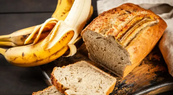 Pyszne, wilgotne ciasto bananowe, które zawsze się udaje. Obok leżą dojrzałe banany, gotowe do pieczenia.