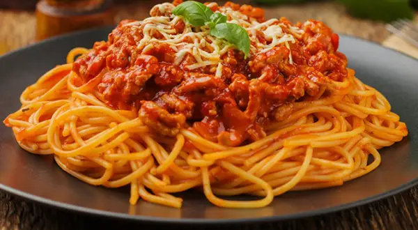 Pyszne spaghetti bolognese z mielonym mięsem, polane sosem pomidorowym i posypane serem. Idealne pytanie: jakie mięso do spaghetti?