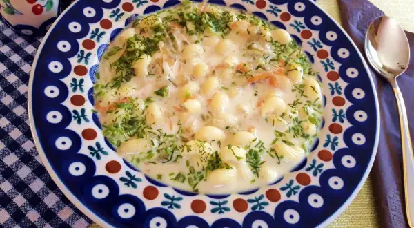 Pyszna zupa na wywarze z golonki z makaronem i koperkiem, podana w ozdobnym talerzu.