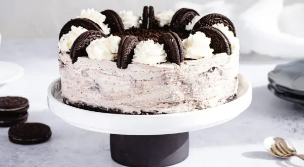 Pyszny sernik Oreo, ozdobiony bitą śmietaną i ciasteczkami. Idealny przepis na deser!