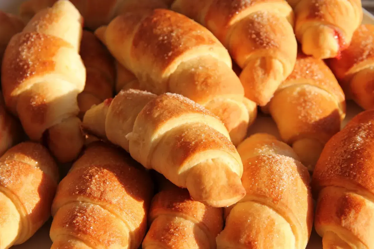 Mięciutkie rogaliki drożdżowe, posypane cukrem, kuszą swoim wyglądem. Idealne na śniadanie lub deser. Przepis na nie jest prosty!