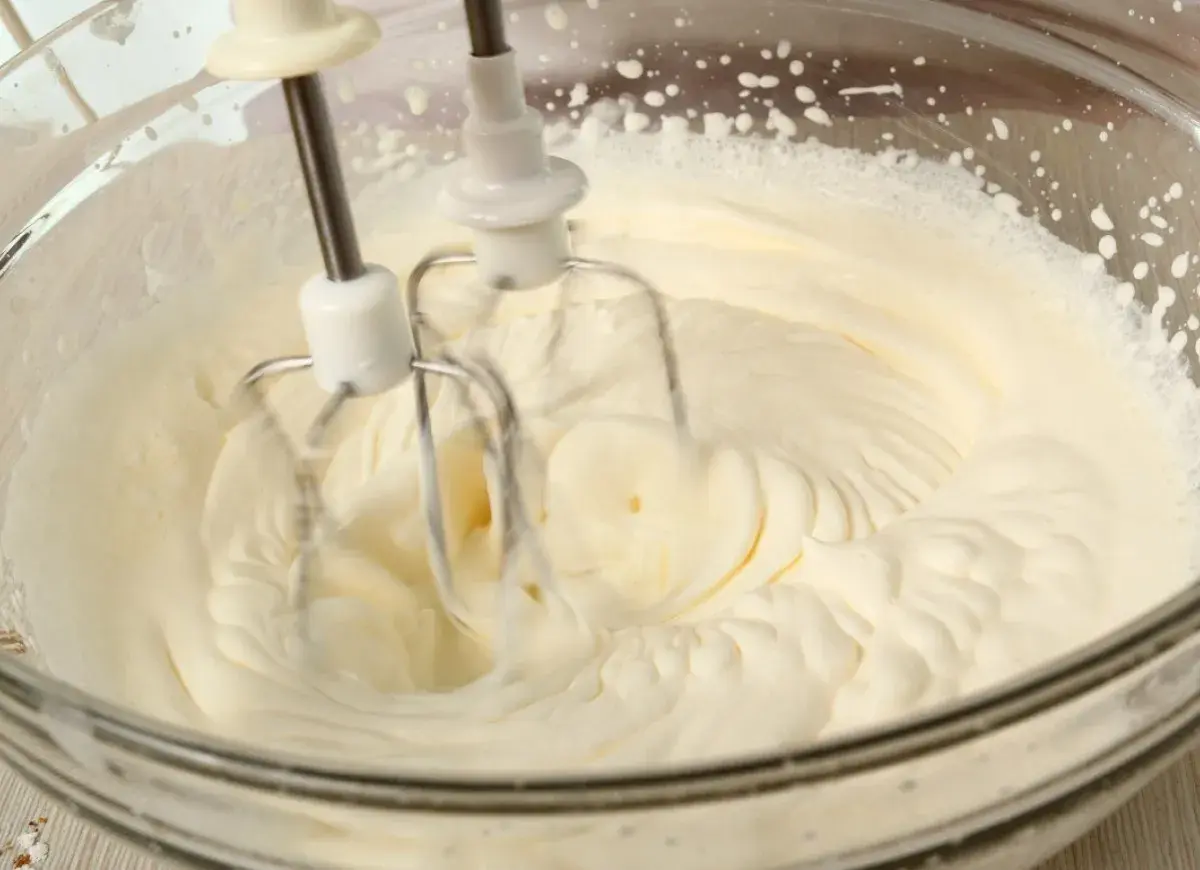 Ubity krem śmietankowy do tortu bez mascarpone, przygotowywany mikserem w szklanej misie.