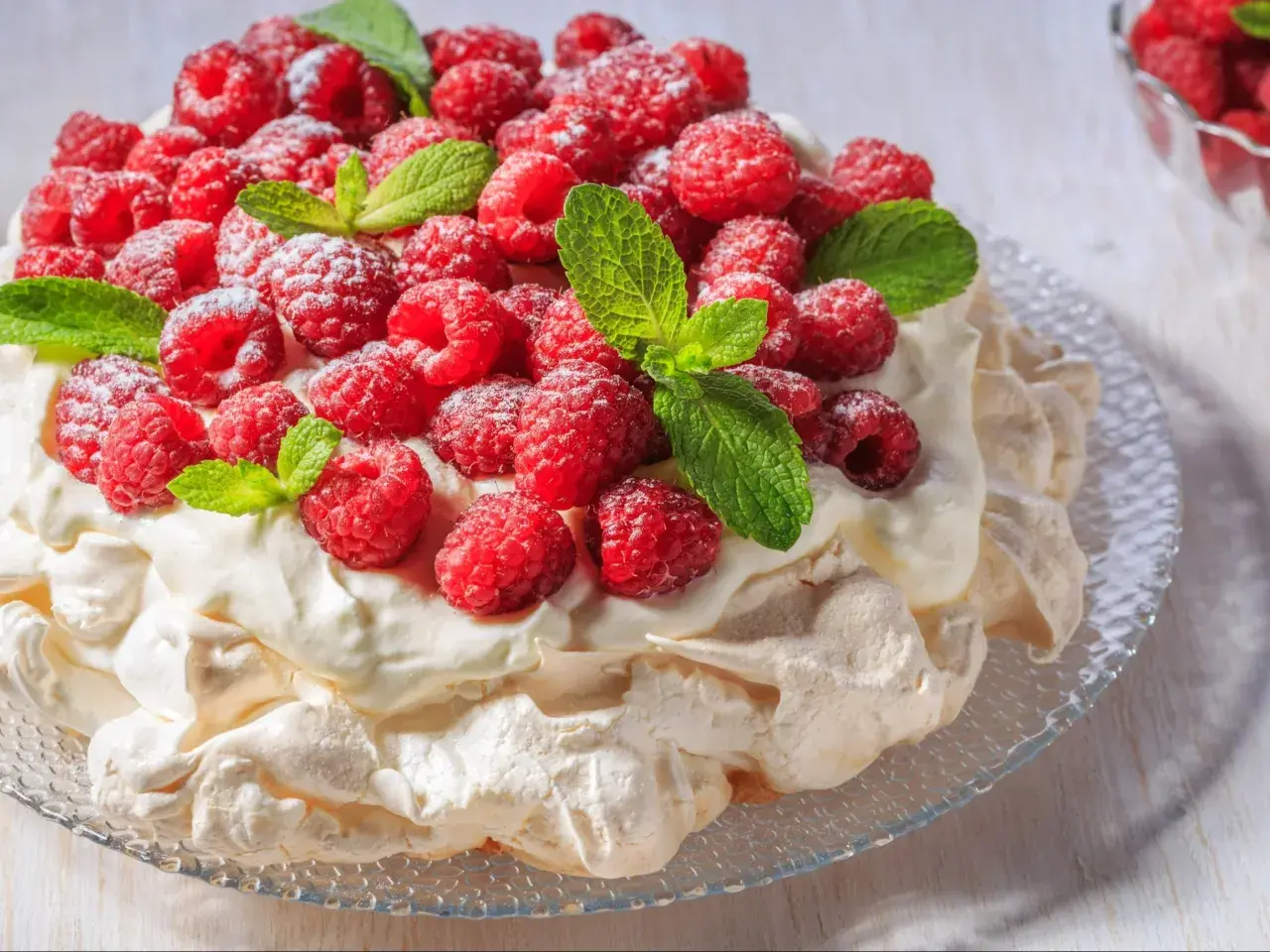 Beza Pavlova, która zawsze wychodzi, obficie udekorowana malinami i listkami mięty, posypana cukrem pudrem.