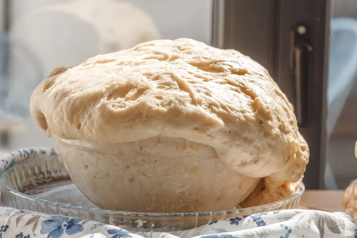 Wyrośnięte ciasto drożdżowe w szklanej misie, gotowe do pieczenia. Idealne na ciasto drożdżowe przepis.
