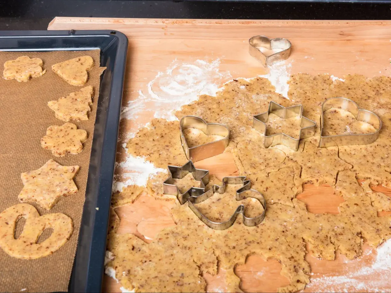 Kruche ciasteczka z mielonymi orzechami włoskimi w kształcie gwiazdek, serduszek i choinek, gotowe do pieczenia.