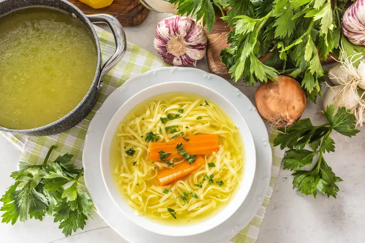 Aromaticzny rosół z makaronem i marchewką, podany w białej misce. Czy rosół jest lekkostrawny? Tak, to idealna, rozgrzewająca potrawa.