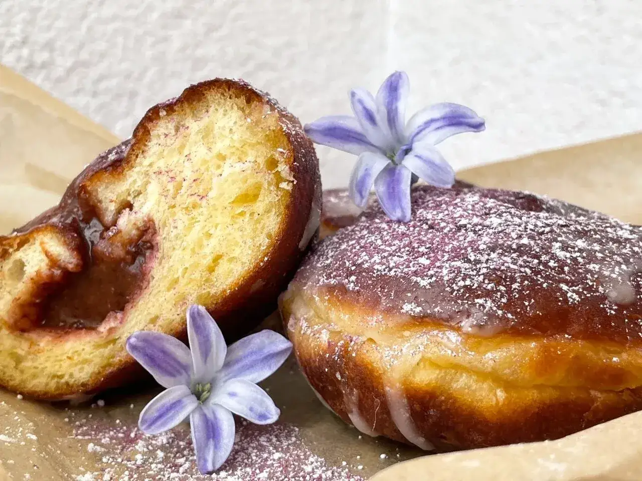 Puszyste pączki z dżemem, posypane cukrem pudrem i ozdobione kwiatami. Stary przepis na pączki, który zawsze się sprawdza.