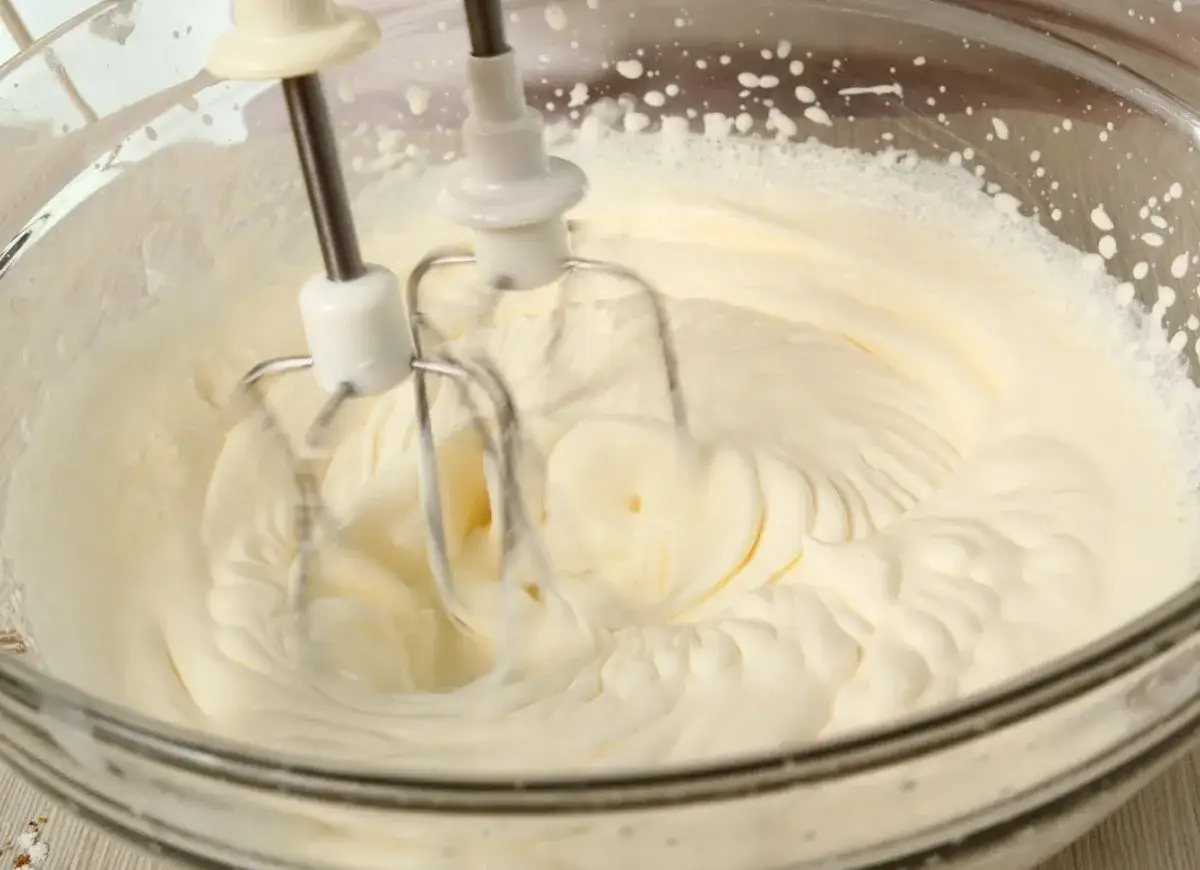 Ubity krem śmietankowy do tortu bez mascarpone, przygotowywany mikserem w szklanej misie.