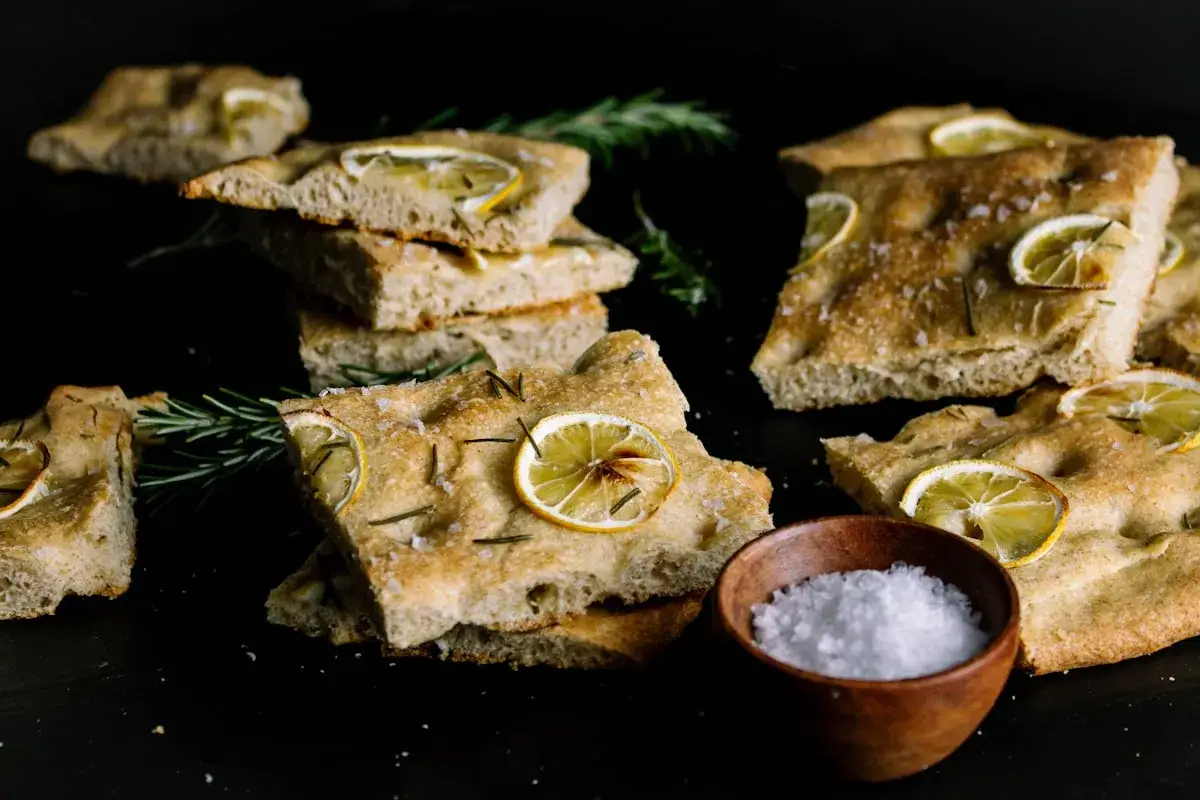 Oryginalna włoska focaccia przepis: puszyste kromki z plasterkami cytryny i rozmarynem, posypane solą morską.