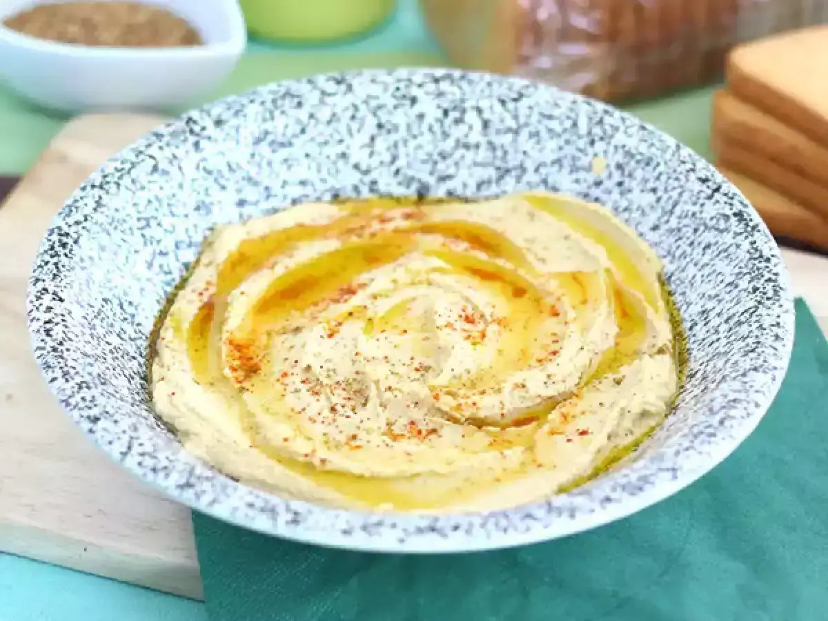 Pyszny, kremowy hummus w misce, polany oliwą i posypany papryką. Idealny do pieczywa, jako dodatek do dania. Prosty przepis na domowy hummus.