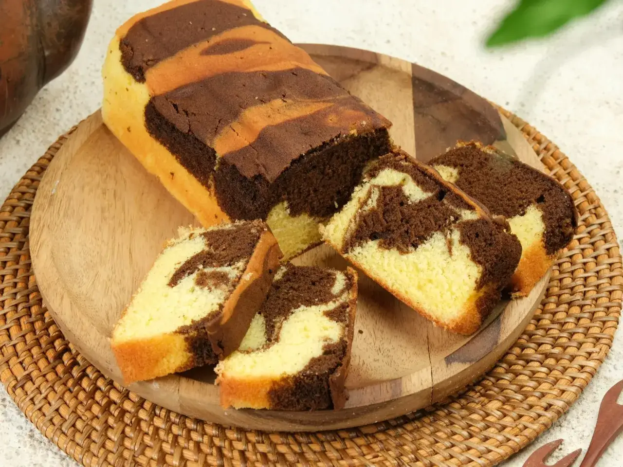 Wilgotna babka marmurkowa na oleju, pokrojona na kawałki, prezentuje swoje czekoladowo-waniliowe wzory. Idealna na podwieczorek.