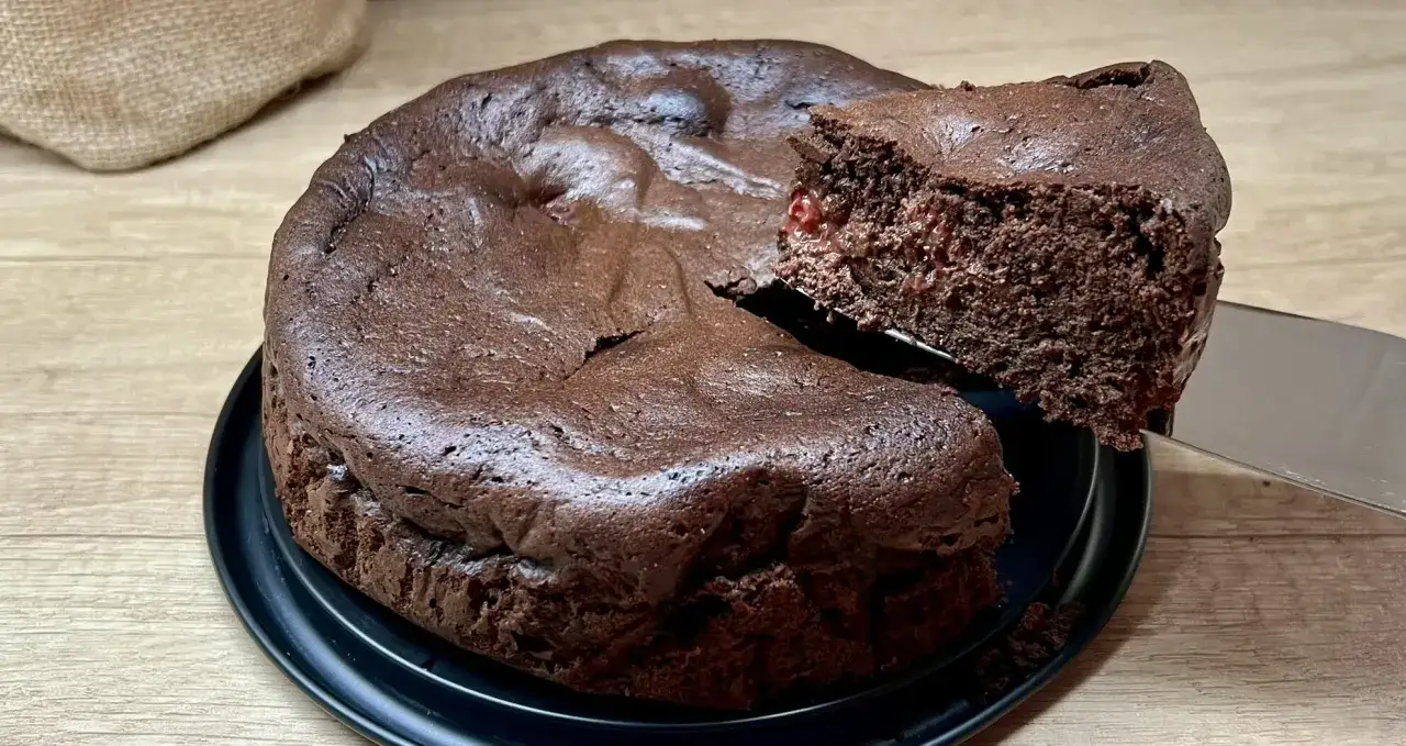 Puszysty brownie z wiśniami, idealny na prosty przepis. Kawałek ciasta jest podnoszony łopatką, ukazując wilgotne wnętrze.
