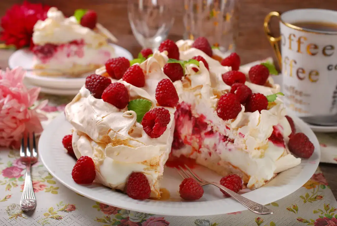 Pyszny tort bezowy z mascarpone i bitą śmietaną, udekorowany malinami. Idealny na deser!