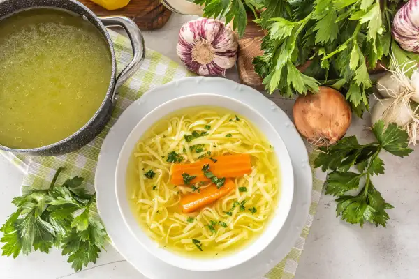 Aromaticzny rosół z makaronem i marchewką, podany w białej misce. Czy rosół jest lekkostrawny? Tak, to idealna, rozgrzewająca potrawa.